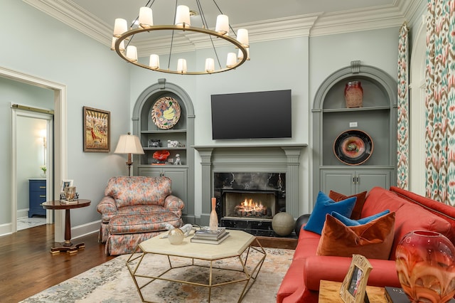 sitting room featuring crown molding, built in shelves, wood finished floors, baseboards, and a notable chandelier