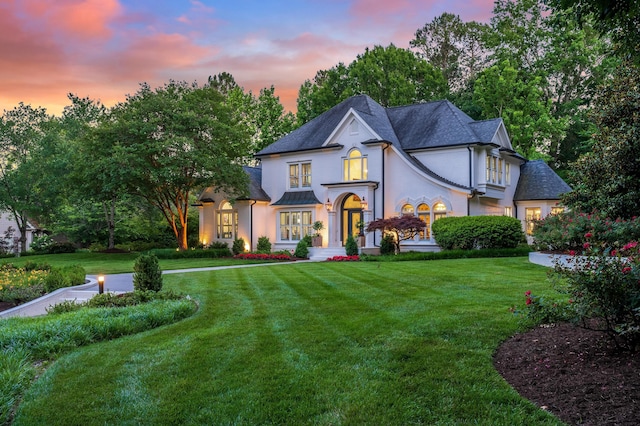 french country inspired facade featuring a lawn, stucco siding, and a standing seam roof