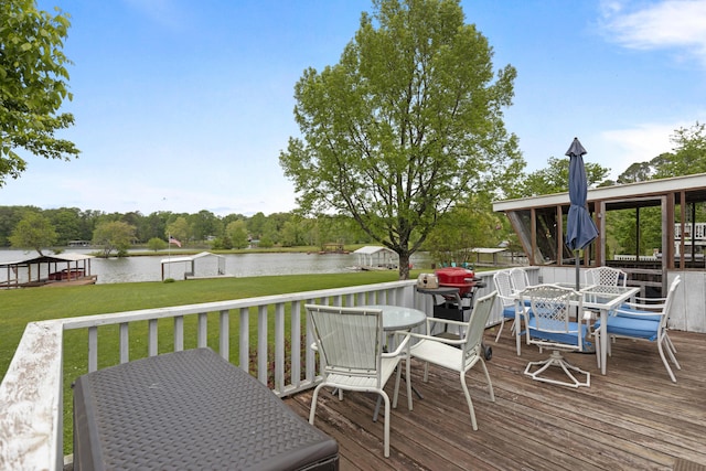 deck featuring outdoor dining space, a water view, and a yard