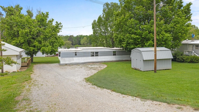 view of front of house with an outdoor structure, driveway, a shed, and a front yard
