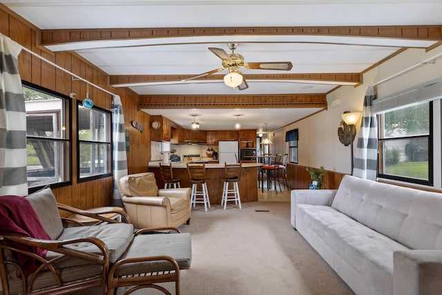 living room with plenty of natural light, light colored carpet, and beamed ceiling