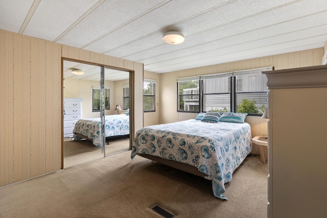 carpeted bedroom featuring a textured ceiling, visible vents, wallpapered walls, and a closet