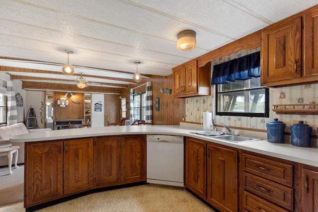kitchen featuring white dishwasher, light countertops, a peninsula, and a sink