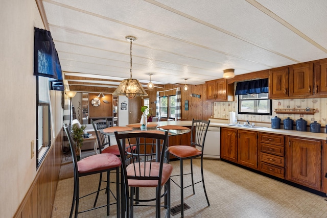 kitchen featuring plenty of natural light, a sink, brown cabinets, and white dishwasher