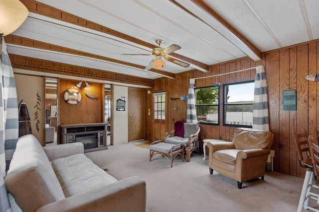 living room featuring wood walls, carpet, a ceiling fan, and beam ceiling