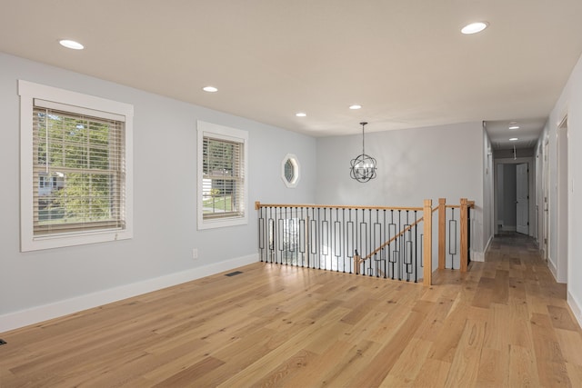 spare room featuring a chandelier and light wood-type flooring