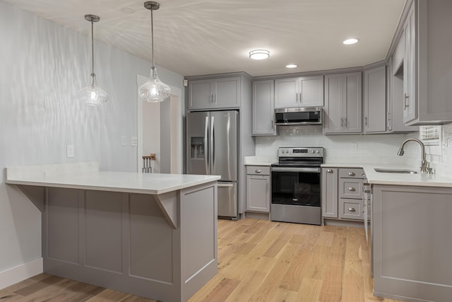 kitchen featuring stainless steel appliances, sink, light hardwood / wood-style flooring, and kitchen peninsula