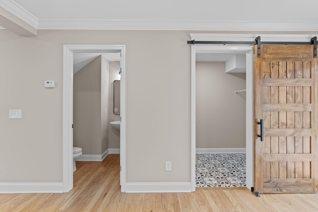 interior space with hardwood / wood-style floors, a barn door, and crown molding