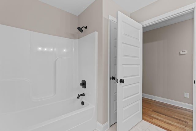 bathroom featuring hardwood / wood-style floors and washtub / shower combination