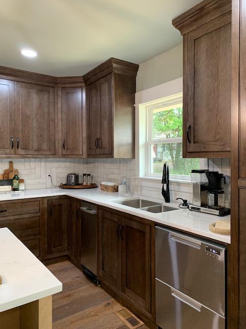 kitchen featuring backsplash, hardwood / wood-style floors, stainless steel dishwasher, and sink