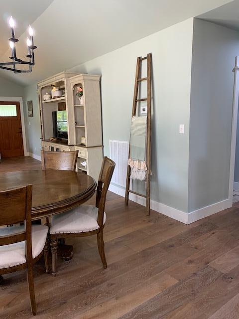 dining room featuring lofted ceiling, a chandelier, and dark hardwood / wood-style floors