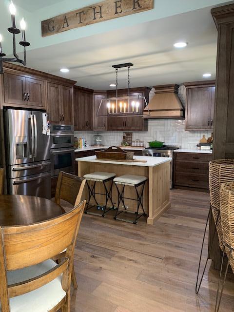 kitchen with a center island, premium range hood, dark hardwood / wood-style floors, appliances with stainless steel finishes, and decorative light fixtures