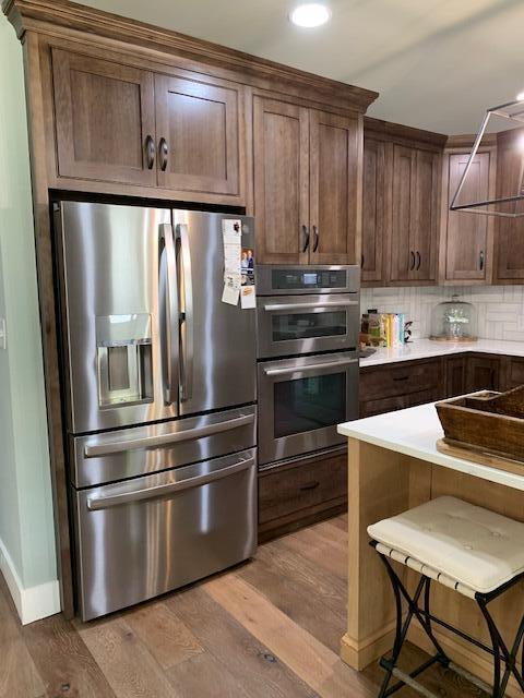 kitchen featuring a kitchen bar, decorative backsplash, stainless steel appliances, and light hardwood / wood-style flooring