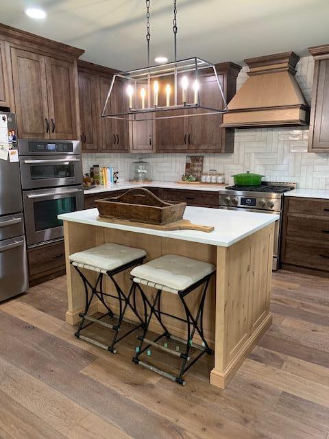 kitchen featuring a center island, dark wood-type flooring, stainless steel appliances, a breakfast bar area, and custom exhaust hood