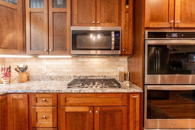 436 Oak Hills Drive Lots 4.5 & 6, Spring City, TN 37381 - kitchen with stainless steel appliances, brown cabinets, decorative backsplash, and glass insert cabinets