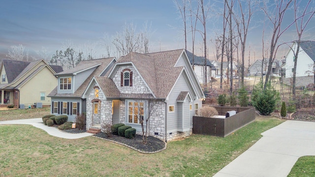 view of front of house with fence, a front lawn, concrete driveway, stone siding, and crawl space