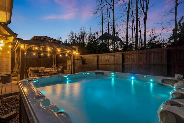 view of pool featuring a gazebo, a hot tub, outdoor lounge area, and a fenced backyard