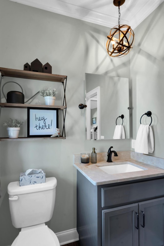 bathroom with vanity, toilet, baseboards, and a chandelier