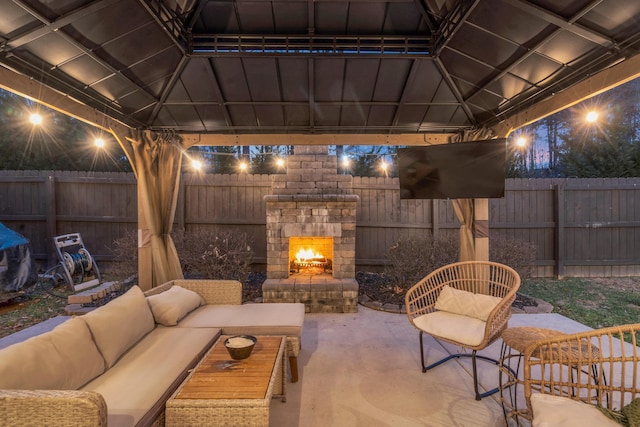 view of patio / terrace featuring a gazebo, an outdoor living space with a fireplace, and a fenced backyard