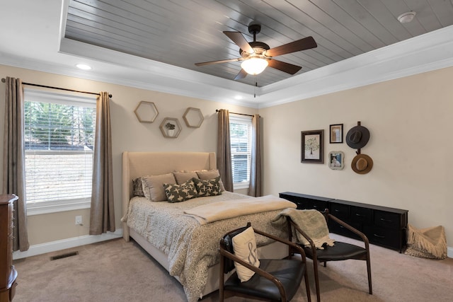 bedroom featuring a tray ceiling, multiple windows, and light colored carpet