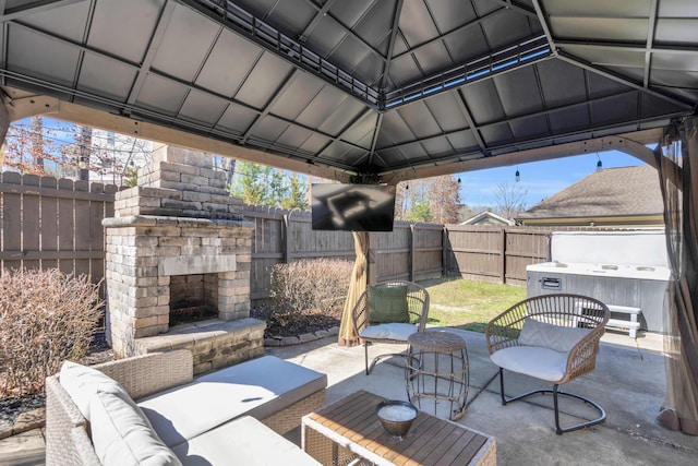 view of patio / terrace featuring a gazebo, an outdoor living space with a fireplace, and a fenced backyard