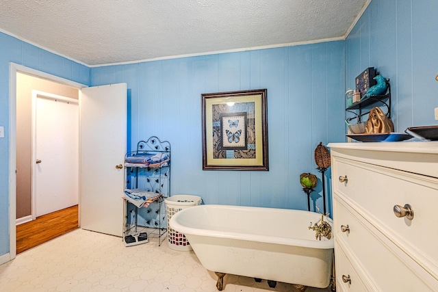 bathroom with a tub to relax in, ornamental molding, and a textured ceiling