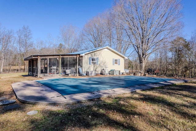 rear view of house with a lawn, a covered pool, a sunroom, and a patio area