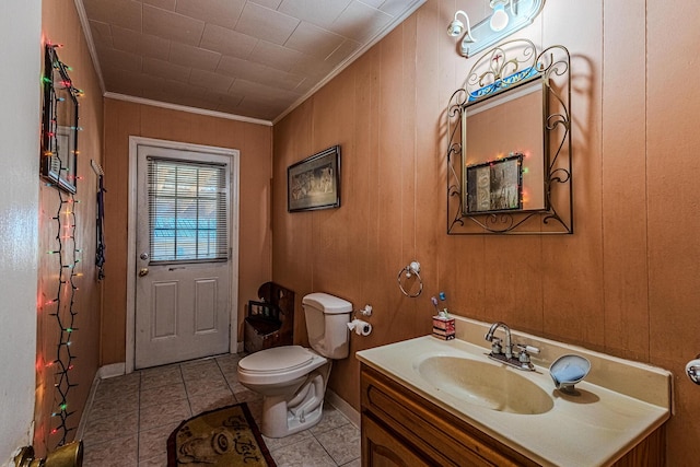 bathroom with crown molding, tile patterned flooring, toilet, vanity, and wooden walls