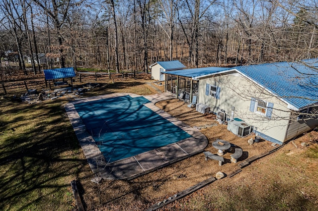 view of pool featuring a lawn, a storage shed, and central AC