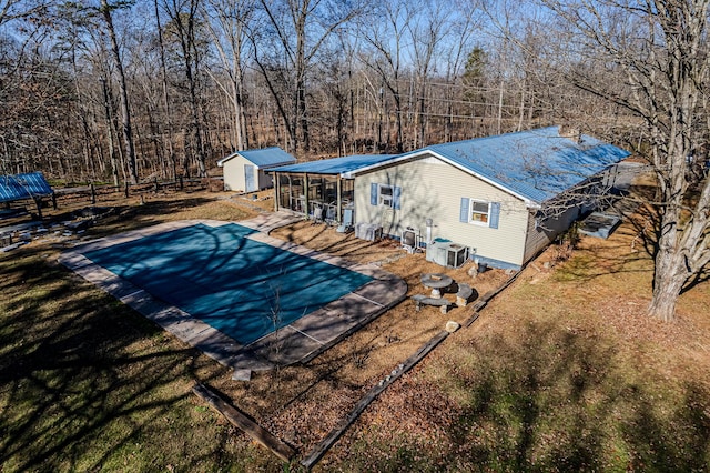 view of swimming pool featuring a patio area, central AC unit, a lawn, and a storage shed