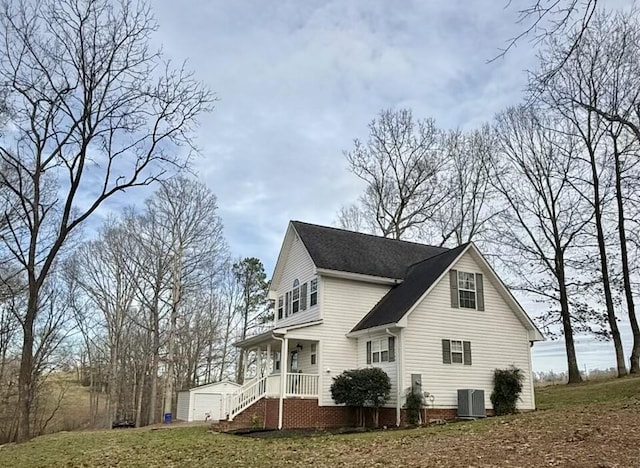 view of side of property featuring a yard, central AC unit, a porch, and a detached garage