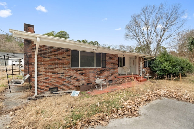 view of front of home featuring brick siding, crawl space, and a chimney