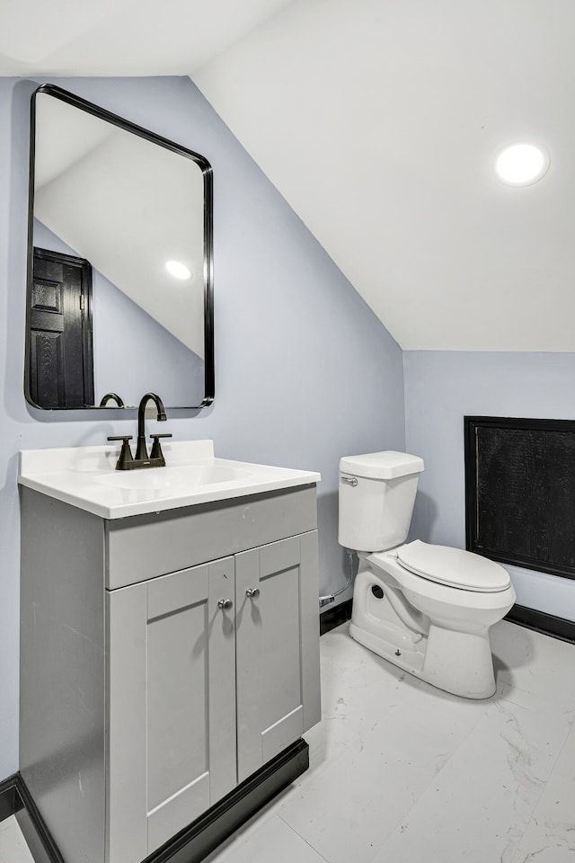 bathroom with vanity, toilet, and vaulted ceiling