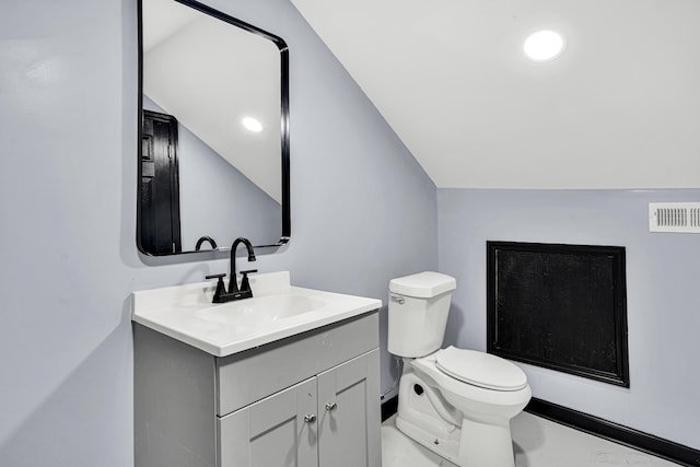 bathroom with vanity, toilet, and lofted ceiling