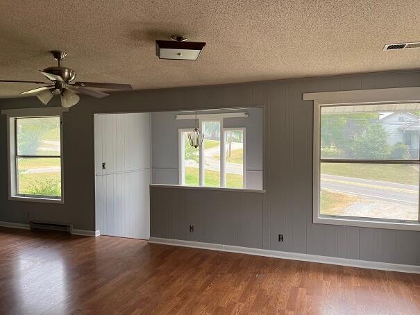 spare room featuring baseboard heating, ceiling fan, a textured ceiling, and hardwood / wood-style flooring