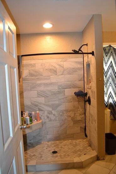 bathroom featuring tiled shower and tile patterned flooring