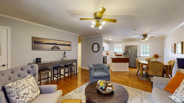 living room with wood-type flooring, ornamental molding, and ceiling fan