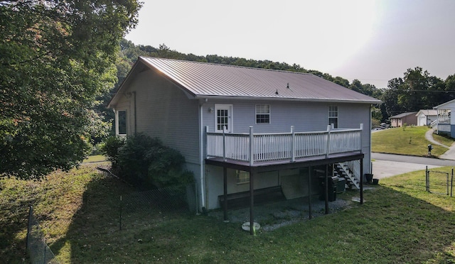 back of property featuring a deck and a lawn