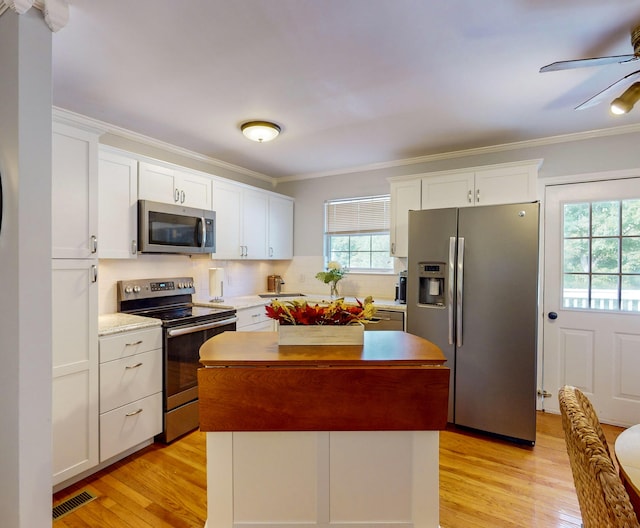 kitchen featuring a wealth of natural light, white cabinets, and appliances with stainless steel finishes