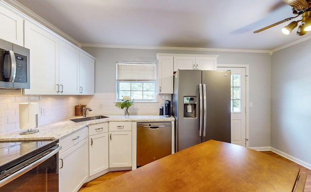 kitchen with sink, tasteful backsplash, ornamental molding, appliances with stainless steel finishes, and white cabinets