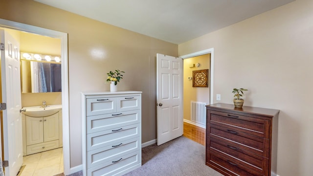 carpeted bedroom featuring ensuite bathroom and sink