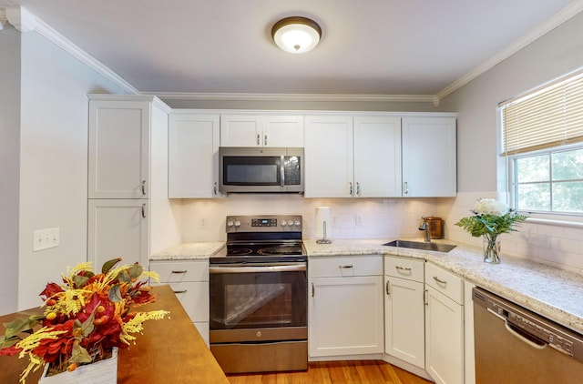 kitchen with ornamental molding, appliances with stainless steel finishes, sink, and backsplash