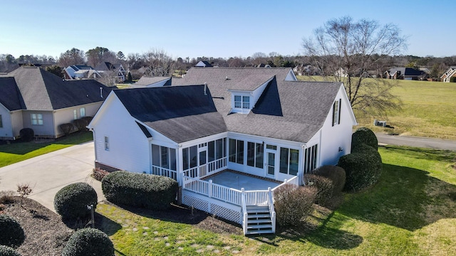 back of property featuring a sunroom, a wooden deck, and a lawn