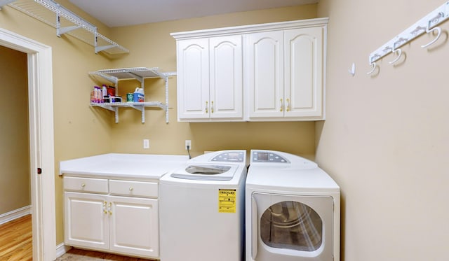 clothes washing area with washer and clothes dryer, cabinets, and light wood-type flooring