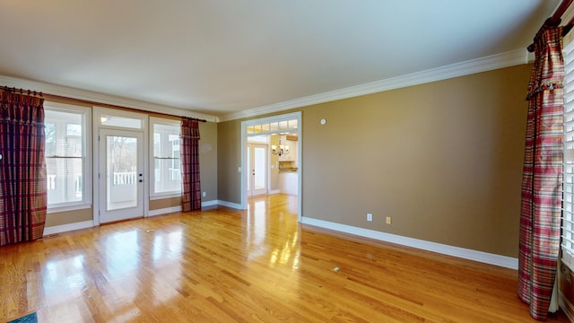 spare room with crown molding, a chandelier, and light hardwood / wood-style floors