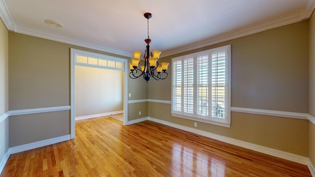 spare room featuring a chandelier, light hardwood / wood-style flooring, and ornamental molding