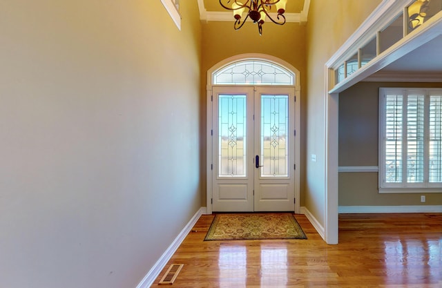 doorway featuring hardwood / wood-style flooring, crown molding, and an inviting chandelier