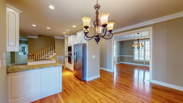 kitchen with light stone countertops, white cabinets, stainless steel appliances, and ornamental molding