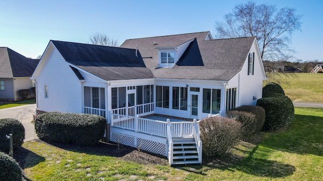 back of property with a sunroom, a wooden deck, and a lawn