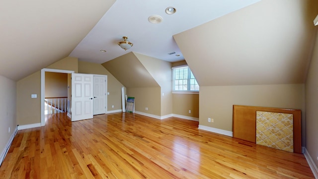 additional living space featuring light wood-type flooring and vaulted ceiling